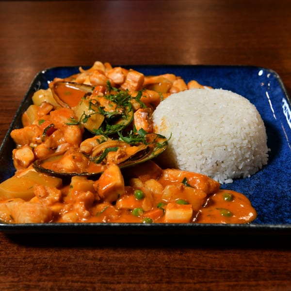 Seafood stew with mussels, shrimp, and vegetables in a red sauce, served with white rice.